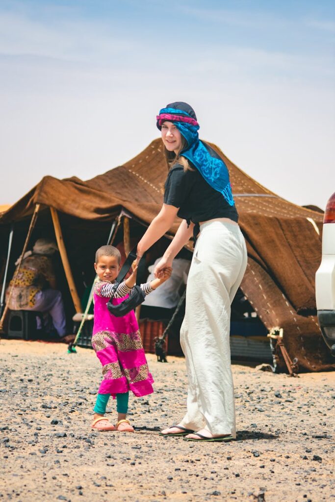 Smiling woman and child holding hands in a Moroccan desert camp. 2 Days Tour from Marrakech To Zagora ,morocco travel