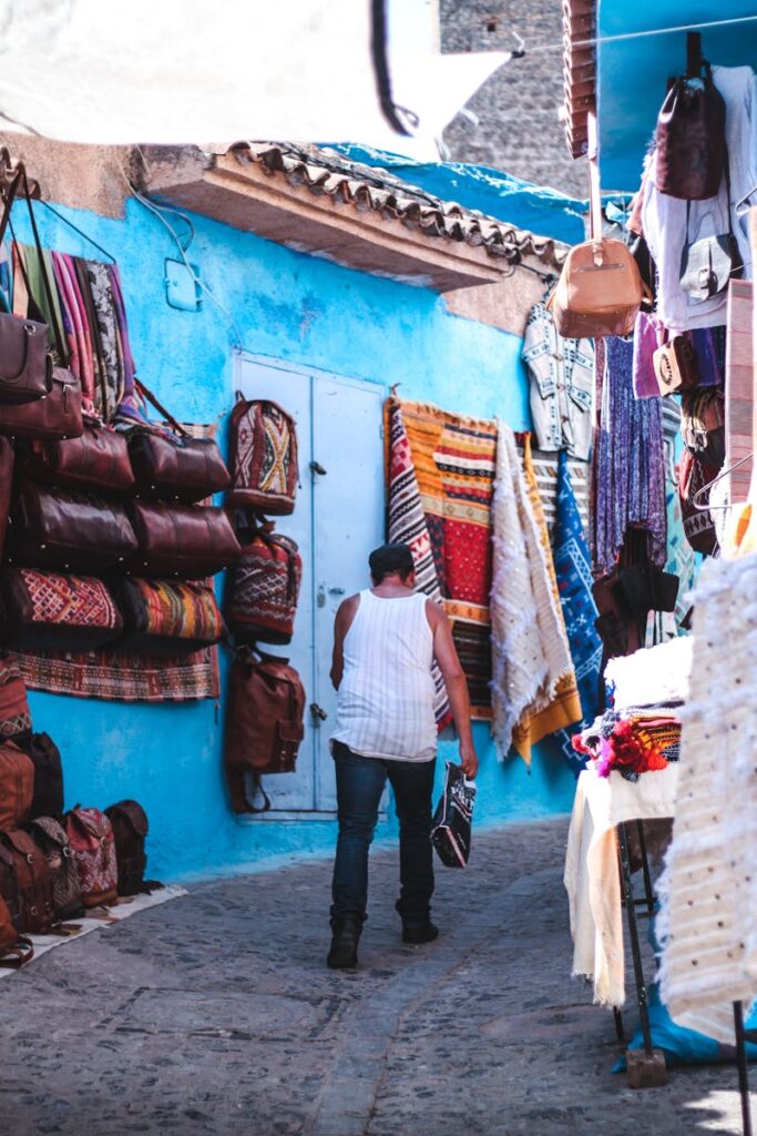 Explore the lively market alley filled with textiles and bags in Chefchaouen, Morocco travel ,12 days tour from Casablanca