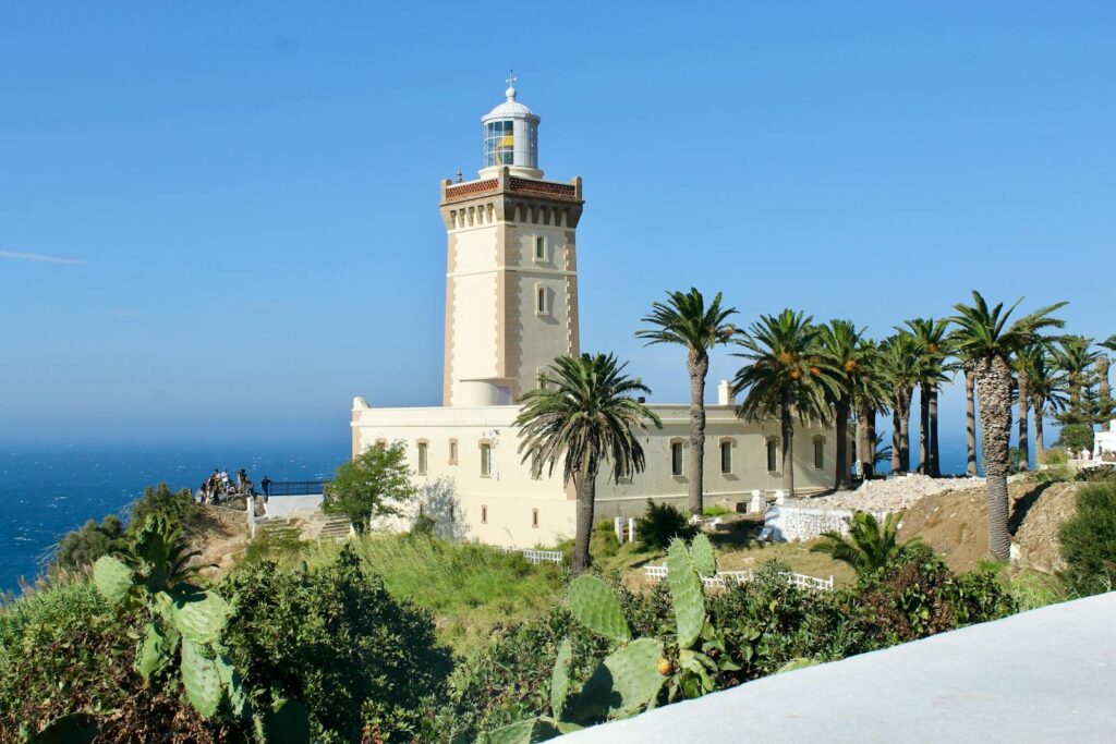 A scenic view of Cape Spartel Lighthouse surrounded by lush palm trees on a sunny day in Morocco travel 5 Days desert tour from Marrakech