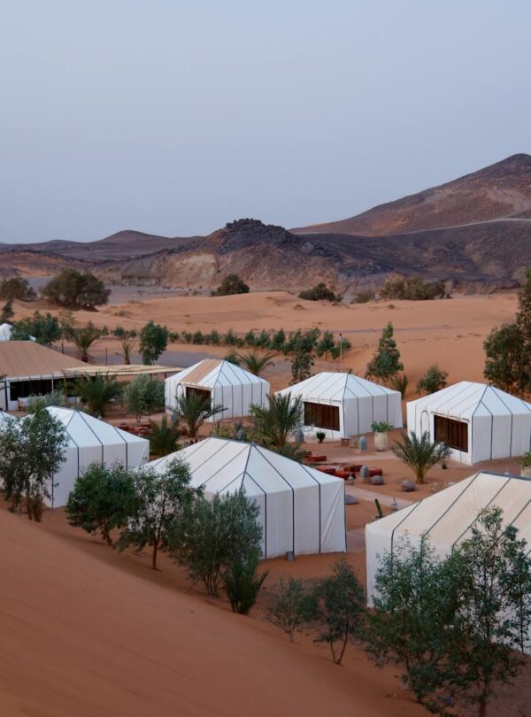 Aerial view of luxury tents in desert landscape with hilly background and twilight ambiance.Morocco travel ,Best 7-Day Morocco Trip from Marrakech