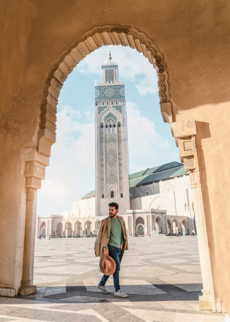Man walking through archway with Hassan II Mosque minaret in Casablanca, Morocco travel , 8 Days Tour From Casablanca